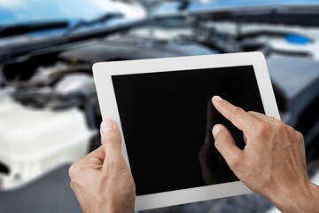 Mechanic worker with digital tablet on car background