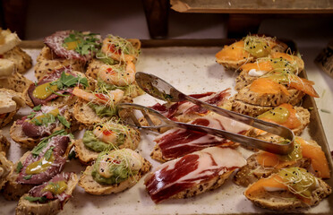 Viele Tapas, kleine Baguettes Stücke mit Belag auf einer Tafel.