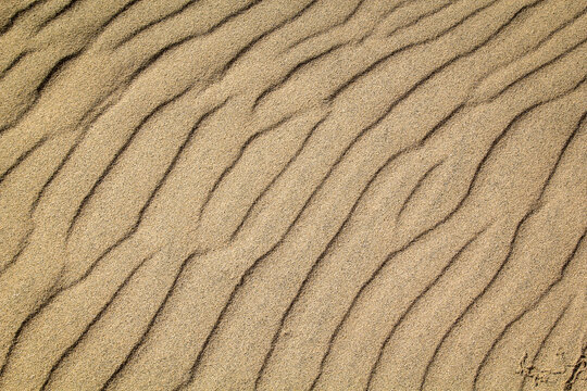 Eine durch Wind und Wellen entstandene Sandtextur am Strand.
