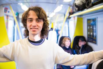 Young happy teenager standing in the middle of a train.