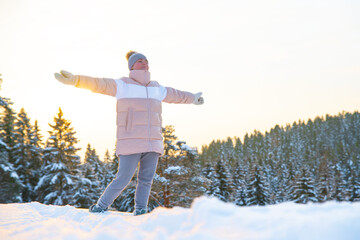 Happy woman, young relaxed carefree free man breathes deep fresh air outdoors on a winter snowy cold frosty day with arms raised, inhales frosty air in a forest or park on a natural background