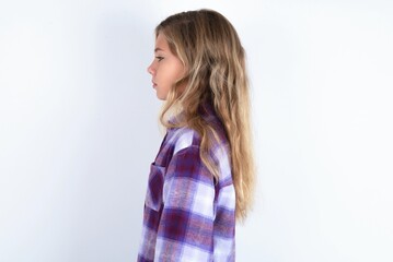 beautiful caucasian teen girl wearing plaid purple shirt over white wall looking to side, relax...