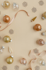 Golden confetti and Christmas toy balls on neutral beige background. Flat lay, top view Christmas holidays background with copy space