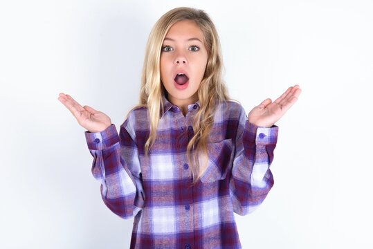 Surprised Terrified Beautiful Caucasian Teen Girl Wearing Plaid Purple Shirt Gestures With Uncertainty, Stares At Camera, Puzzled As Doesn't Know Answer On Tricky Question, People, Body Language