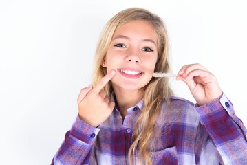 beautiful caucasian teen girl wearing plaid purple shirt over white wall holding an invisible...