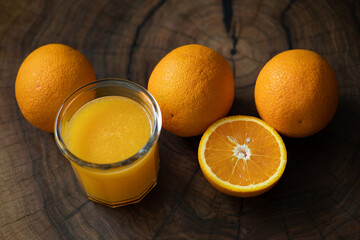Glass of orange juice and oranges on a wooden table