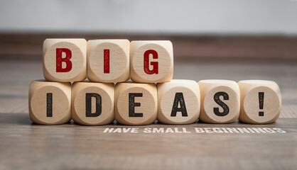 Cubes or dice with big ideas have small beginnings on wooden background