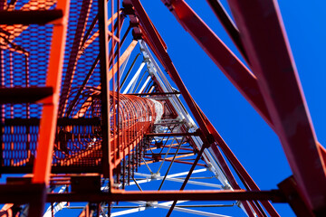 The communication tower stands against the sky with a bottom-up view. Close-up