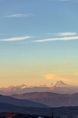 landscape with the peak of Mount Kazbek on the horizon in the rays of the setting sun