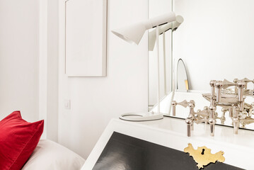 Detail of a black and white chest of drawers with lamp and beveled mirror