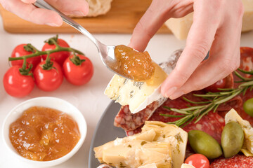 Woman eating Italian antipasti. Charcuterie plate with different types of sausages and cheeses - salami, bresaola, proscuitto, dorblu, parmesan