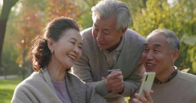 Cheerful senior Chinese adult using smart phones in the park,4K