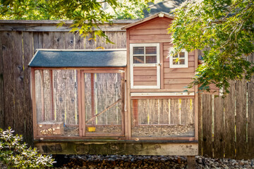 Cute wooden and wire chicken coop in back of residential yard with privacy fence and foliage © Susan Vineyard 