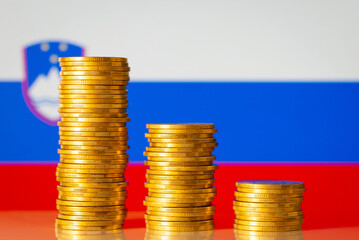 Golden coin stacks against flag of Slovenia. Financial recession of Slovenia, negative GDP rate of...
