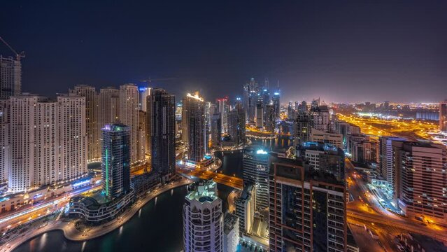 Panorama of various skyscrapers in tallest recidential block in Dubai Marina aerial during all night timelapse with artificial canal. Many towers and yachts