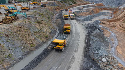 Excavator working on earth moving at open pit mining on amazing sunset background. Backhoe digs...