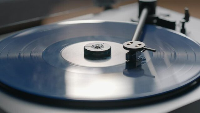Blue vinyl record spinning and playing music on a black gramophone

