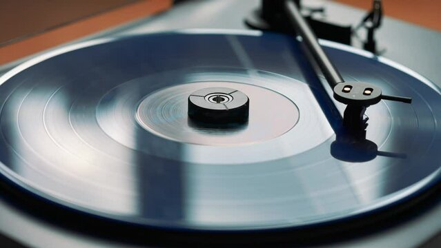 Blue vinyl record spinning and playing music on a black gramophone
