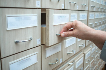 A woman's hand opens a filing cabinet.