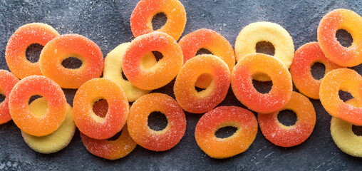 A narrow view of bright colourful sugar coated peach flavoured gummy rings.