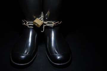 Bound with a old, rusty chains in black rubber boots...