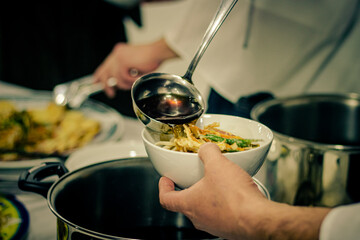 Sao Paulo, SP, Brazil - February 12 2021: Caucasian person serving soup in container with sliced ​​vegetables details.