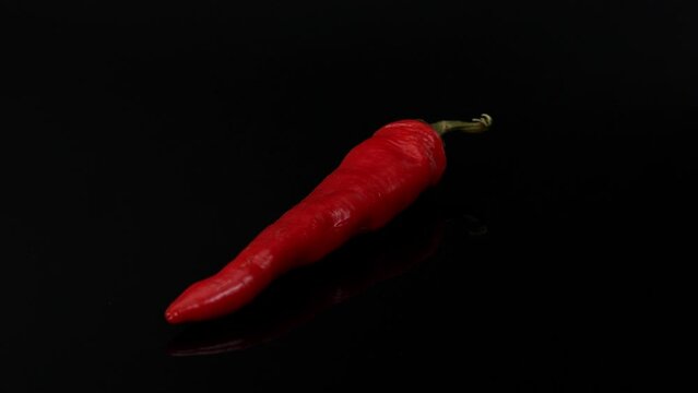 spining chilli peper on the black background, chilli on the black , close-up of chilli  peper