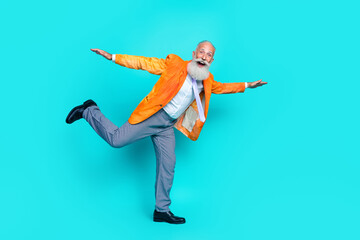 Full size profile portrait of overjoyed aged person stand one leg arm wings isolated on cyan color background