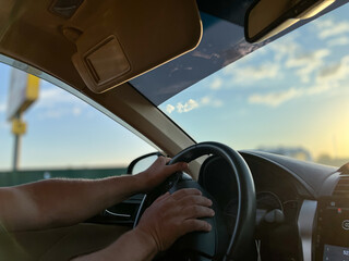 Naklejka premium A man drives a car with his hands on the steering wheel. Road trip, the concept of traveling by car.