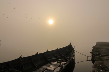 Boot am Steg mit  Vögeln im Nebel mit Sonne