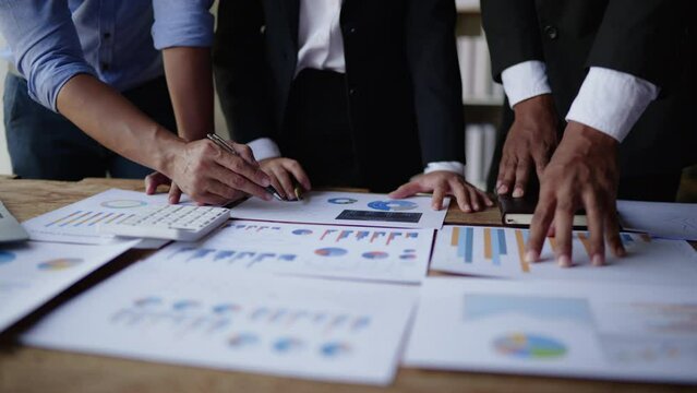 Closeup business people teamwork are working and calculate on their business. Discussed about paperwork that shows chat and graft of accounting statistics, number of cost.