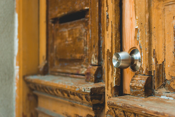 Vintage wood exterior door of an old home entrance with steel doorknob