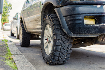 Off road vehicle parked next to sidewalk with a close up on tire