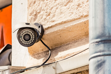 Infrared CCTV security camera mounted on a building exterior wall to monitor suspicious activity...
