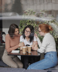 three women comfort each other and help in difficult times. friends talk in a coffee shop and drink...