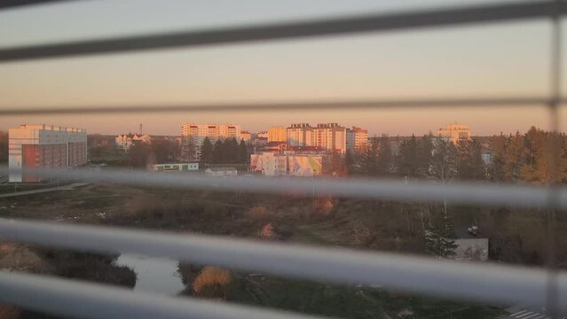 Blinds open to view the sunset over the town