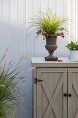 A little cabinet on a terrace in front of a white divider with different decorations