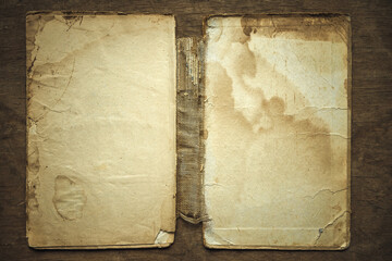 Old paper sheets of an open book. The background of a yellowed vintage book. Restoration of covers.The ragged texture of old paper on a wooden table.