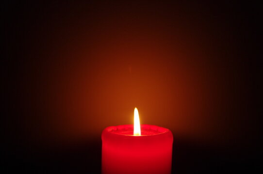 A red candle on a dark background, emphasizing the flame