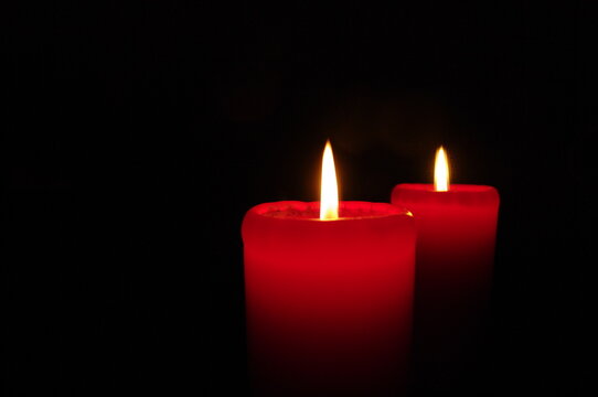 Two red candles on a dark background, emphasizing the flame