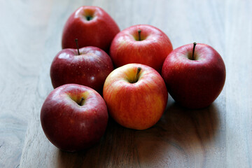 red apples on a wooden table in a pyramid shape, fresh apples on a wooden background