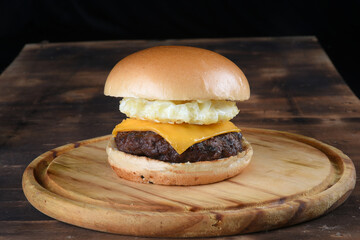 beef burger with sandwich bun salad onion and cheese fast food isolated on wooden table.