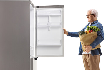 Profile shot of a mature man with a grocery bag opening a fridge