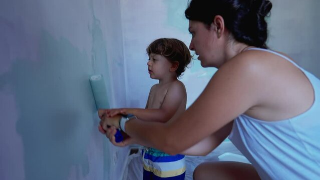 Mother and child painting wall. Parent and kid doing house renovation with paint roller. Closeup paint on apartment wall