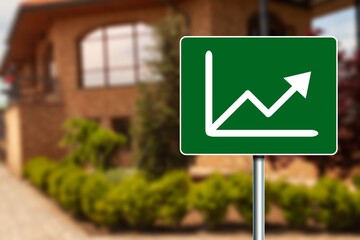 A sign with arrow on house background. Real estate concept.