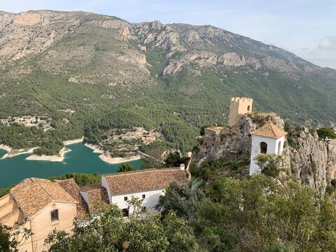 Panoramic view of the Castle of Guadalest, in Alicante, Spain. An old medieval town on top of a mountain.  A large reservoir is in the background.