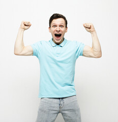 Fototapeta premium Yes. Emotional man shouting shaking fists standing over white background.