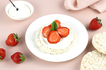 Rice cake with fresh strawberries and Greek yogurt on a pink background, top view. Gluten free, low calorie dessert. Rice cracker with topping