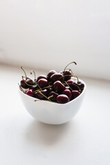 Fresh ripe cherries on a plate on a white background. Vitamins and healthy nutrition