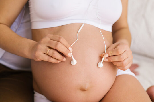 Pregnant woman holding headphones on tummy